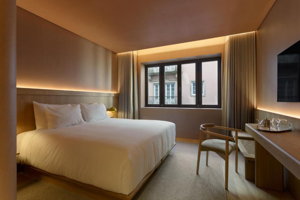 Un dormitorio con una cama y un escritorio y una ventana. en Akeah Porto Centro, en Oporto