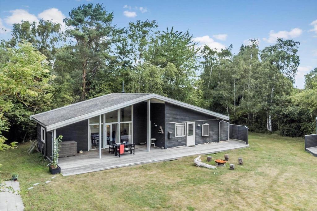 a black tiny house with a deck in a yard at 4317-Stege-Oddermosevej-6 in Stege