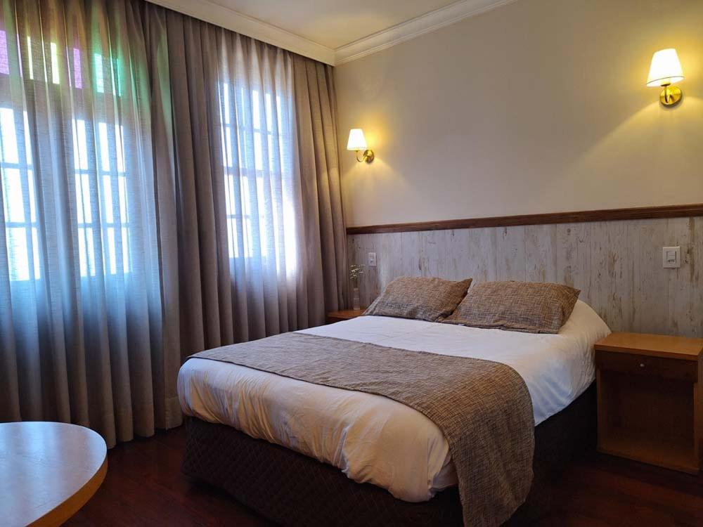 Un dormitorio con una cama grande y dos ventanas. en Boroni Palace Hotel, en Ouro Preto