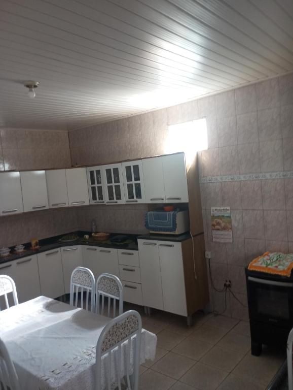 a kitchen with white cabinets and a table and chairs at Cantinho mineiro in Passa Quatro
