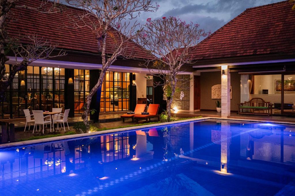 a swimming pool in front of a house at night at The Casa Amaya in Jimbaran