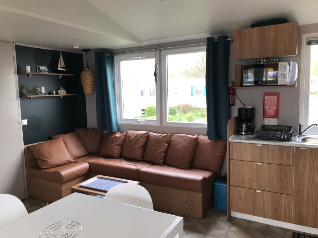 a living room with a brown couch in a kitchen at Le Domaine de Litteau 4 étoiles à LITTEAU emplacement 443 3CH 1SDB 6 personnes in Litteau