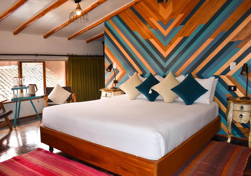 a bedroom with a bed with a colorful wall at Nodo Cusco Garcilaso in Cusco