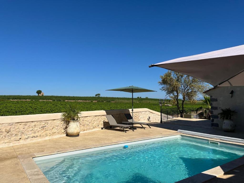 - une piscine avec une terrasse et un parasol dans l'établissement Les Granges Saint Paul, à Lespignan