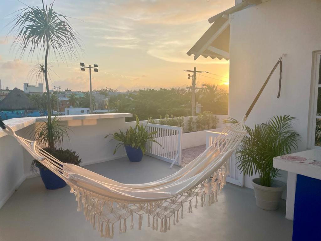 a hammock on a balcony with a sunset in the background at Suites del Mar by Ha in Isla Mujeres