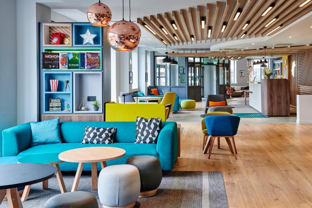 a lobby with a blue couch and tables and chairs at Holiday Inn Belfast by IHG in Belfast