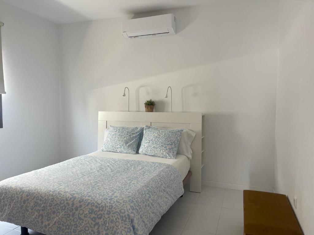 a white bedroom with a bed with two blue pillows at CASA MESANA Nuevo cama King size en playa con AIRE ACONDICIONADO in Playa Honda