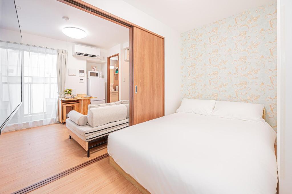 een witte slaapkamer met een bed en een stoel bij Sheath Okachimachi Apartment Hotel in Tokyo