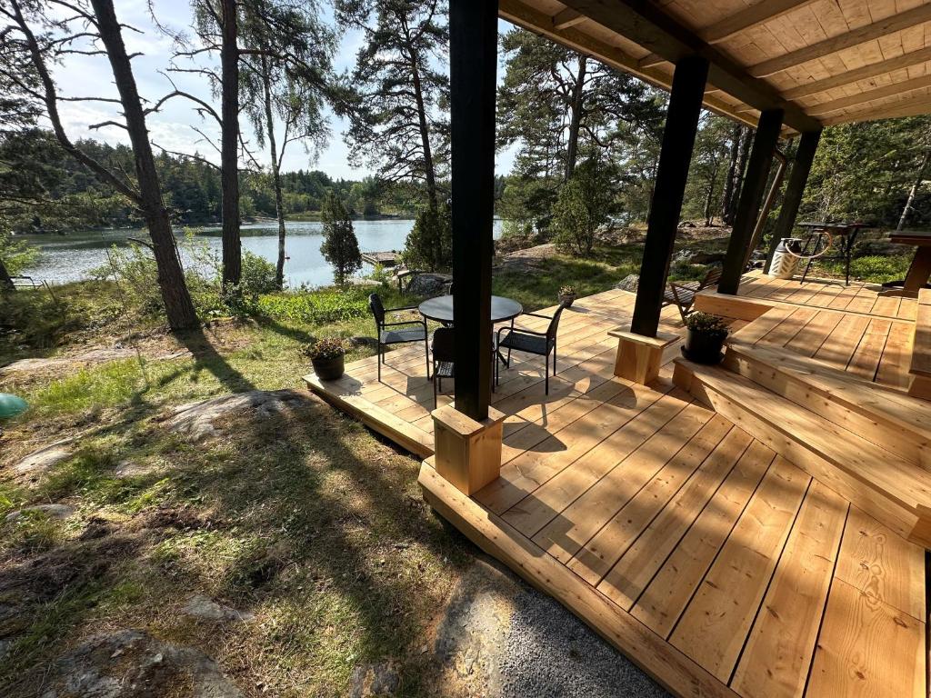 a wooden deck with a table and chairs on it at Kustvy - En Destination intill Havet in Hållnäs