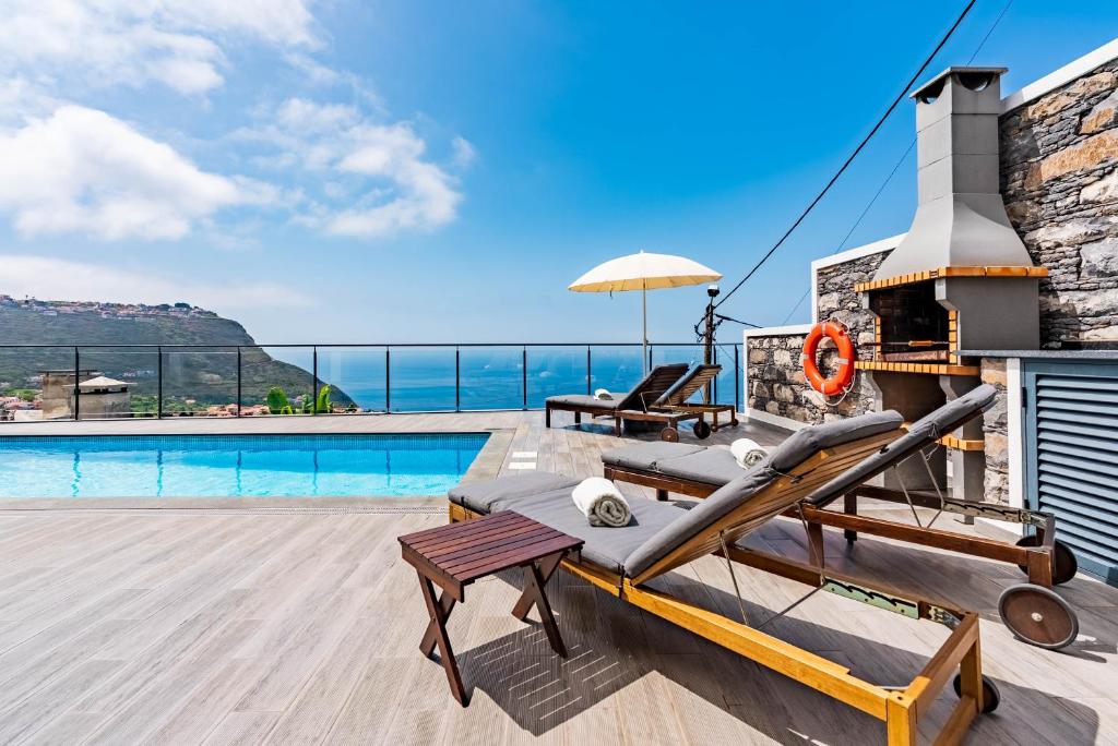 a villa with a swimming pool and a deck with a fireplace at Villa da Bisa with heated swiming pool in Arco da Calheta