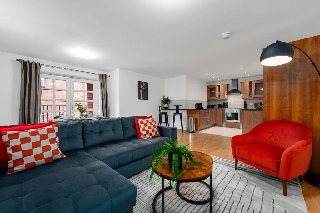 a living room with a blue couch and a red chair at 2 Bed Altrincham Flat Free Parking in Altrincham