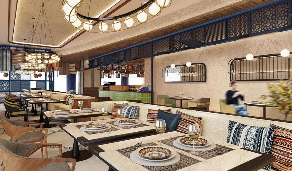 a restaurant with tables and chairs and a person walking in the background at Hotel Indigo Jabal Akhdar Resort & Spa by IHG in Al ‘Aqar