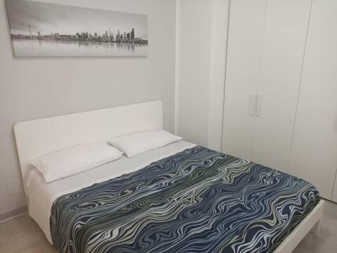 - un lit dans une chambre blanche avec une photo sur le mur dans l'établissement Al Civico 2, à Pordenone