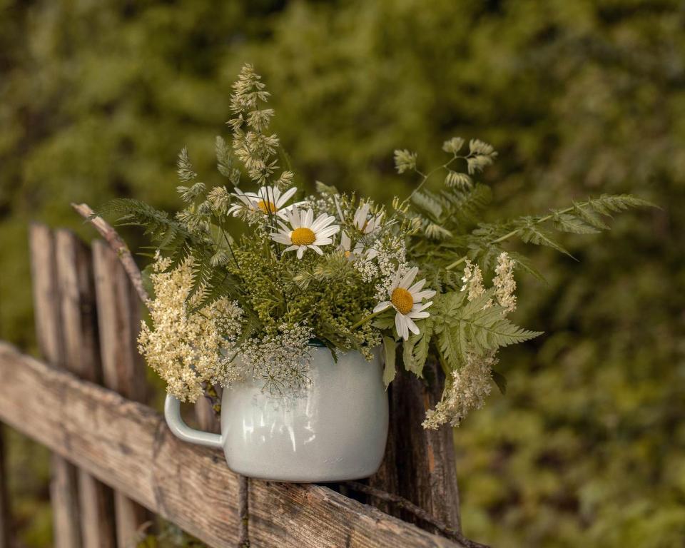a white vase filled with flowers on a fence at Alpenrose in Obermaiselstein