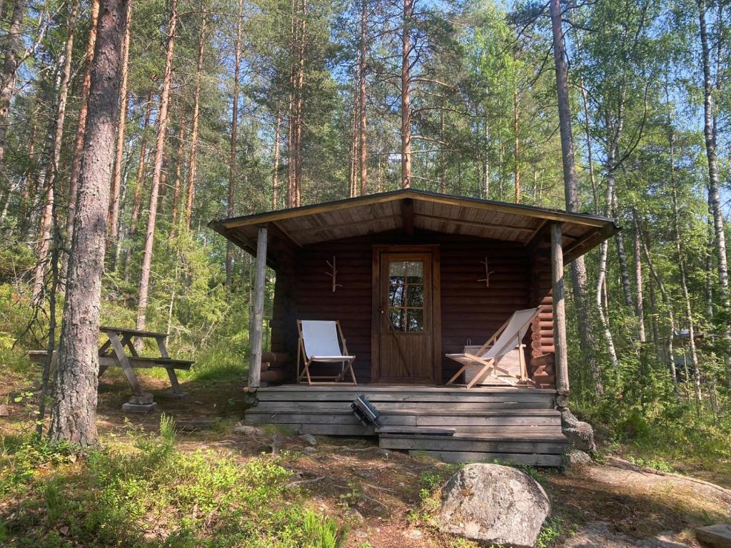 een houten hut met een stoel in het bos bij Metsäsydän mökki 3 Vinksinvonksin 