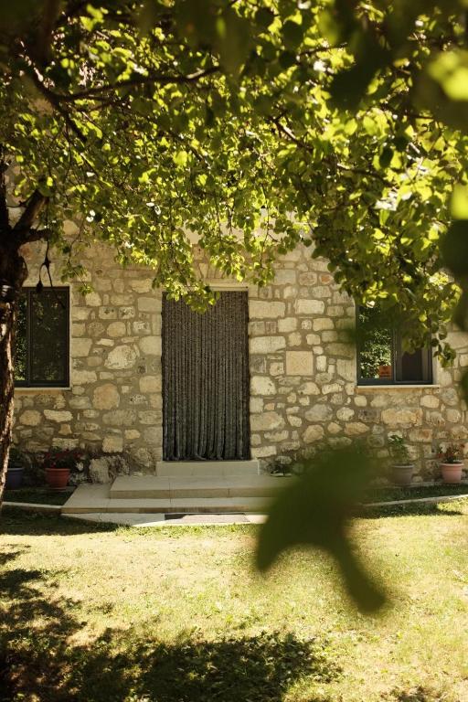a stone building with a window and a tree at Bujtina Milani in Theth
