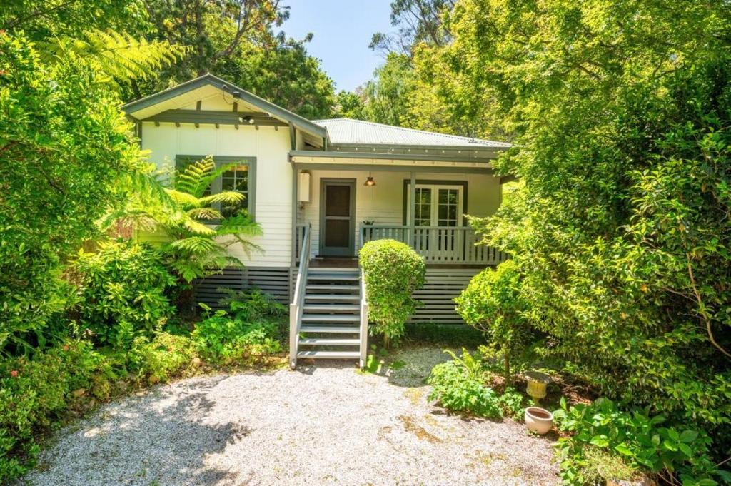 una piccola casa bianca con scale e alberi di River Song a Warburton