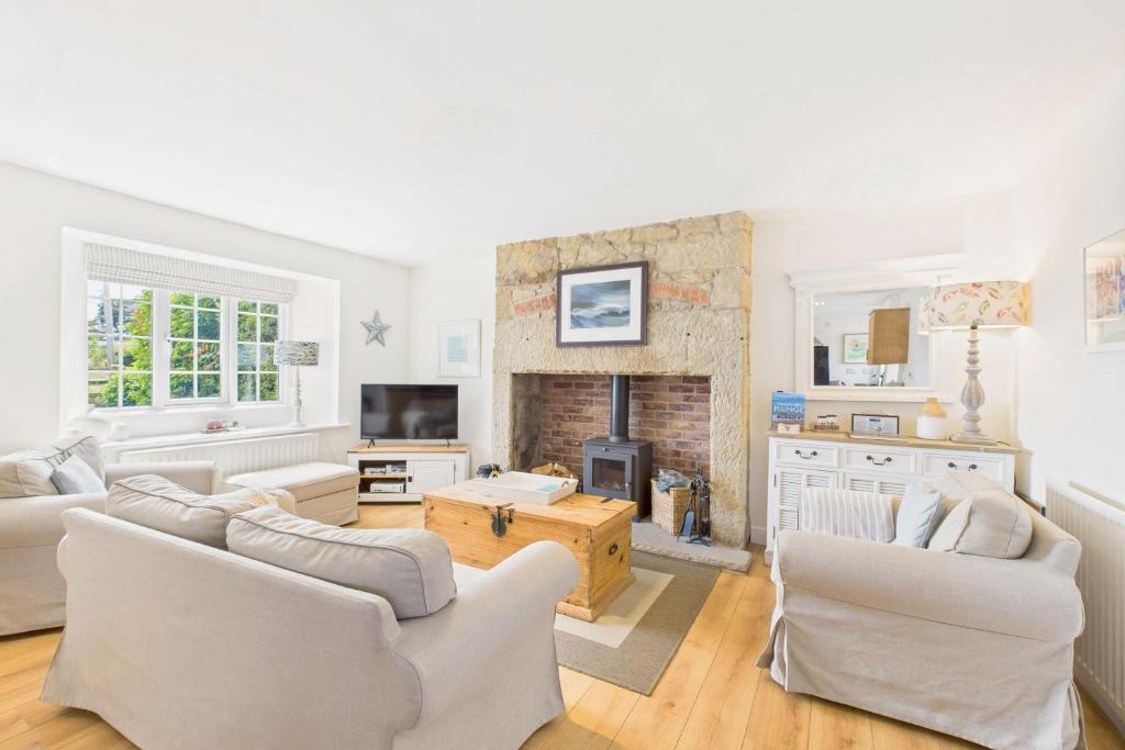 Elle comprend un salon doté d'un mobilier blanc et d'une cheminée. dans l'établissement Host & Stay - Dove Cottage, à Warkworth