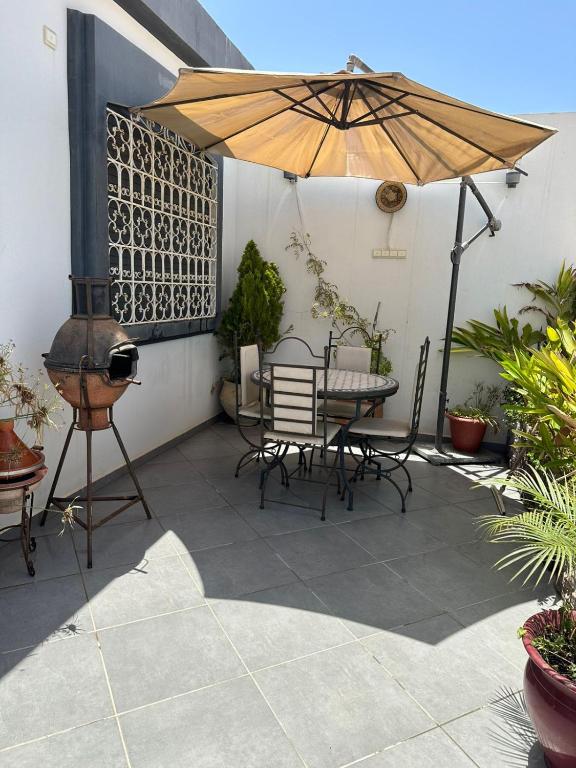 eine Terrasse mit Sonnenschirm und Tisch und Stühlen in der Unterkunft Appartement de charme entre mer et montagne in Oulad Akkou