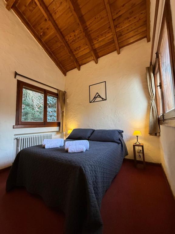 a bedroom with a bed with blue sheets and a window at Nevada Hostel in San Carlos de Bariloche