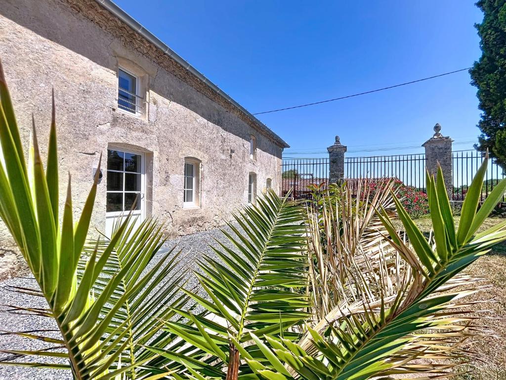 ein Steingebäude mit Palmen davor in der Unterkunft Hortensia - 2 chambres - Charme et Calme au cœur du Blayais in Anglade