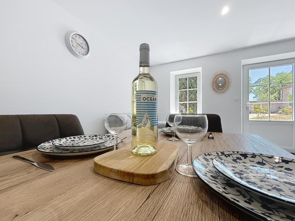 a bottle of wine sitting on a table with glasses at Hortensia - 2 chambres - Charme et Calme au cœur du Blayais in Anglade