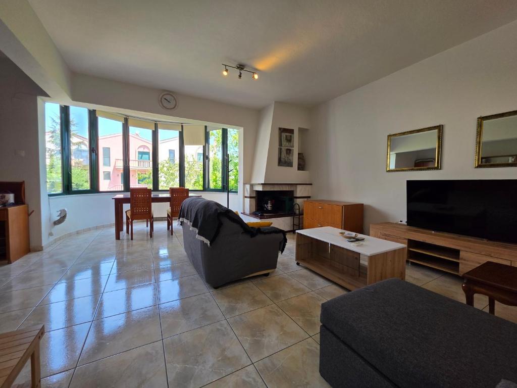 a living room with a couch and a flat screen tv at Alex House Garden in Iraklitsa