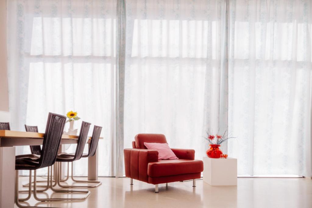 a living room with a red chair and a table at Villeni Panorama Apartment Oktonia in Okhthonía