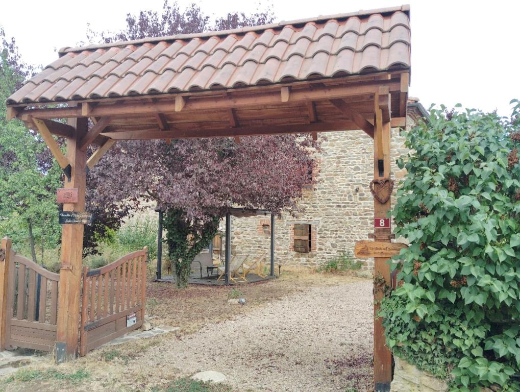 a wooden pergola in a garden with a fence at Les Faes du Bos in Saint-Beauzire