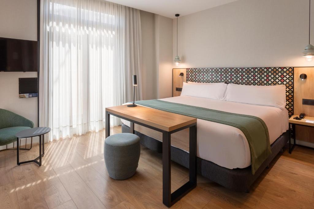 a bedroom with a large bed and a table at Catalonia Excelsior in Valencia