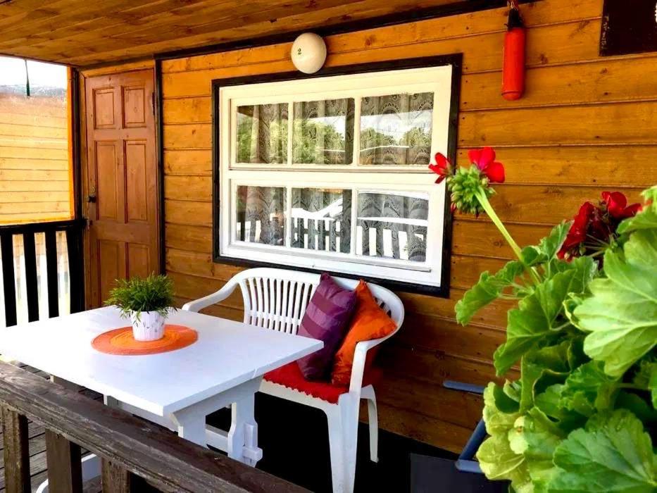 a porch with a white table and a window at Domki Alkana - domek 4 in Nowęcin