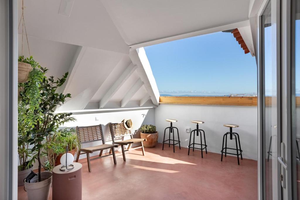 an attic patio with chairs and tables and a window at GuestReady - Fabulous studios near Pink Street in Lisbon