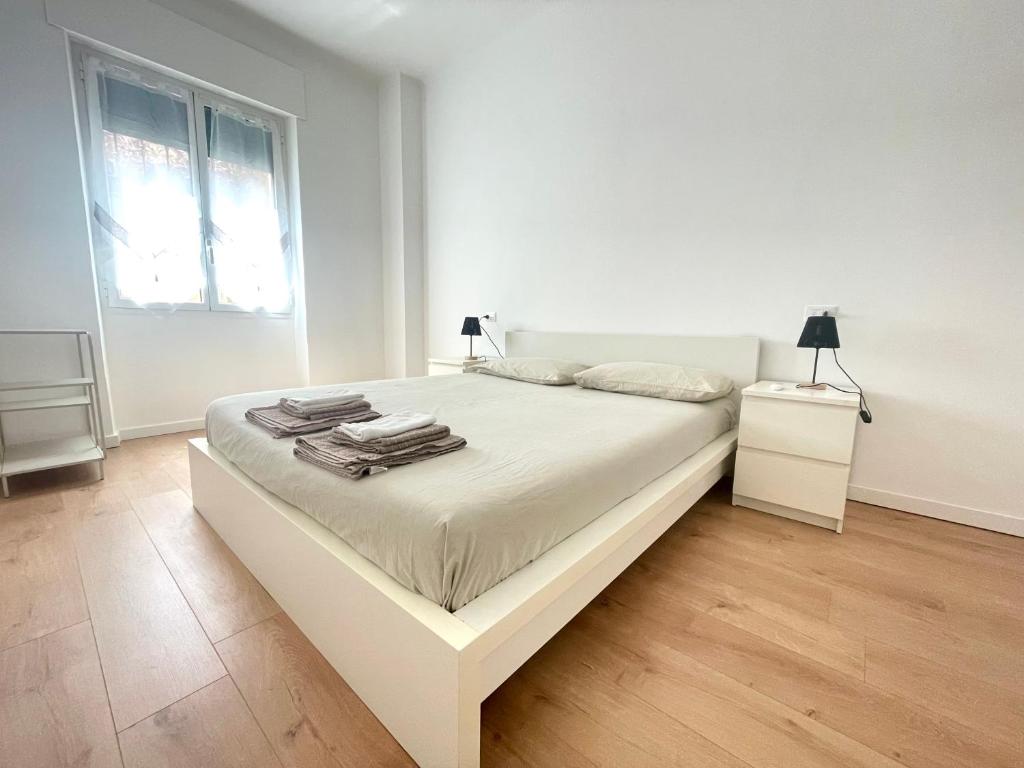 a white bedroom with a large white bed and a window at La casa di Mariposa in Sanremo