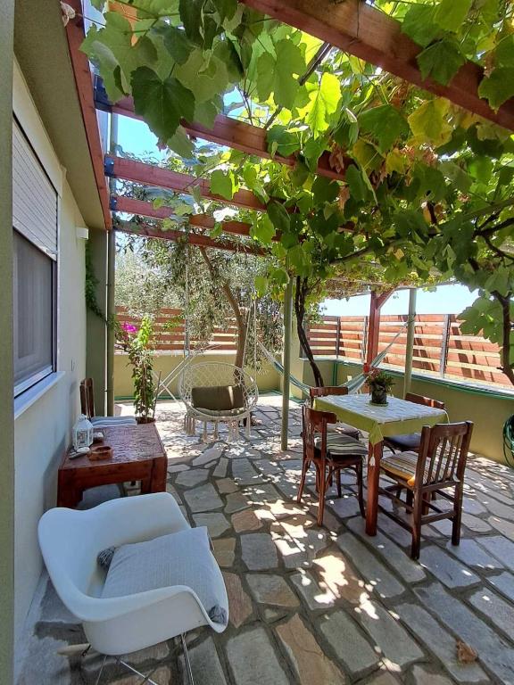 a patio with a table and chairs under a pergola at Green Olive Studios in Agios Mamas