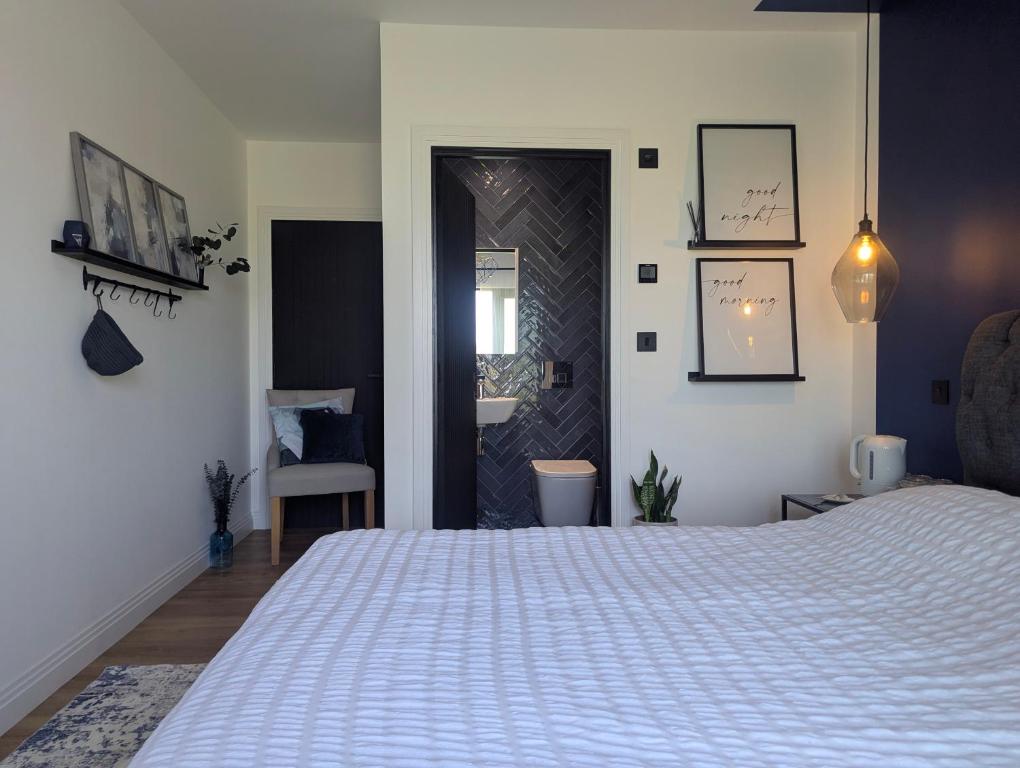 a bedroom with a large white bed and a door at Up Shed - Modern Countryside King-size Ensuite With Own Access in Bradworthy
