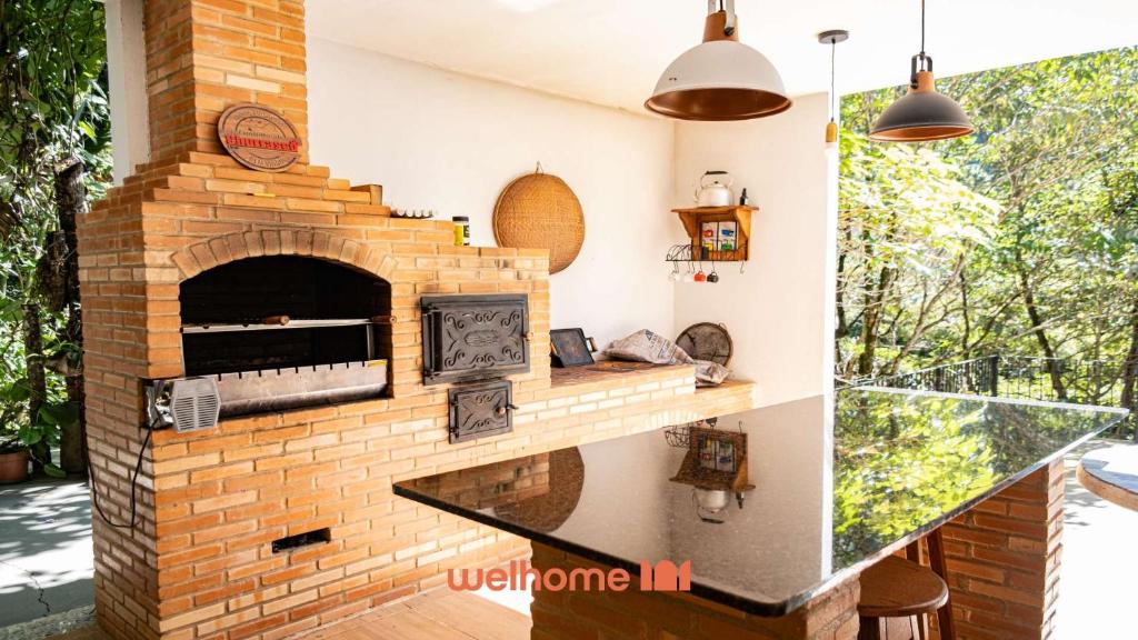 an outdoor brick oven in a patio with pendant lights at Sitio em Domingos Martins com Piscina e Vista in Domingos Martins