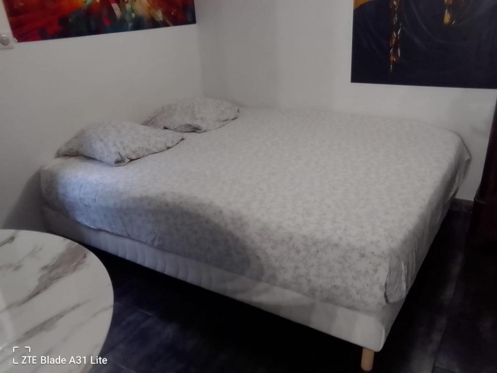 a bed with white sheets and pillows on it at Studio Chaleureux in Neuilly-sur-Marne