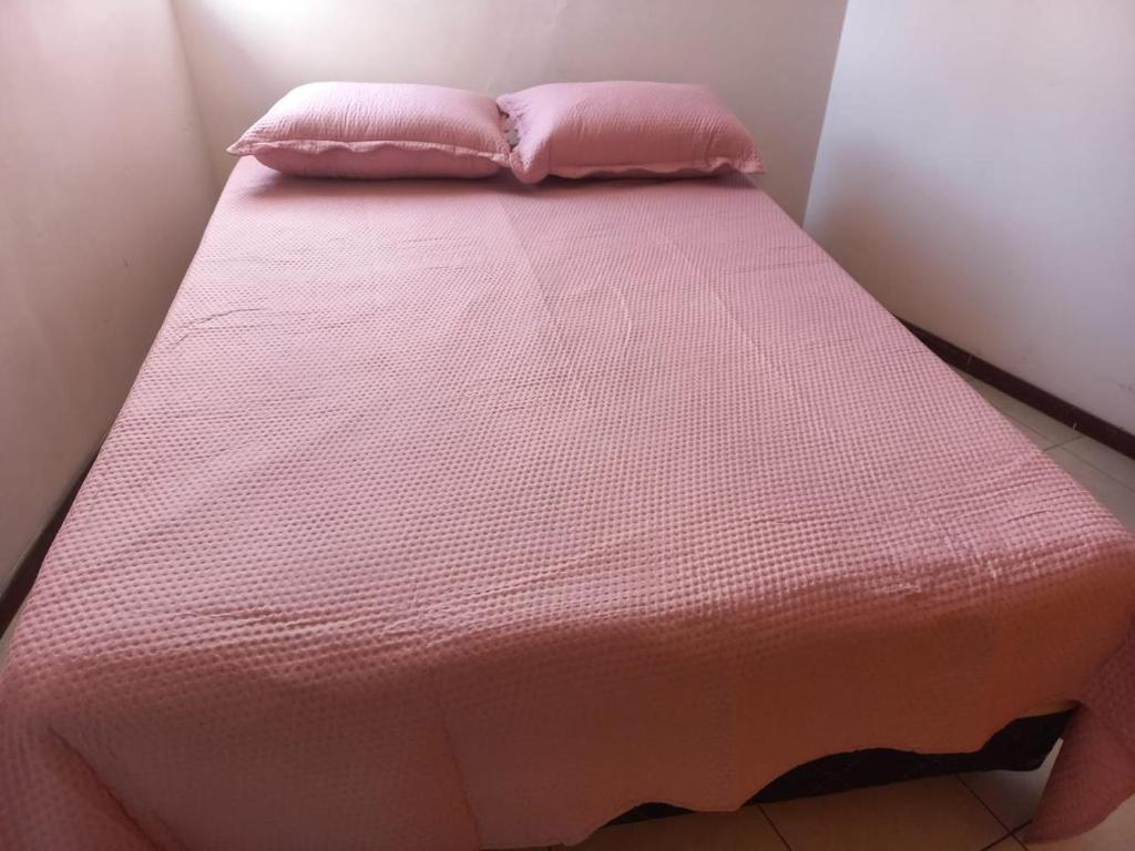 a bed with a pink blanket and two pillows on it at Apartamento pé na areia - João Pessoa -Paraíba in João Pessoa