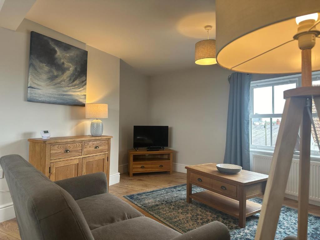 a living room with a couch and a tv at Church Walk View Apartment Filey in Filey
