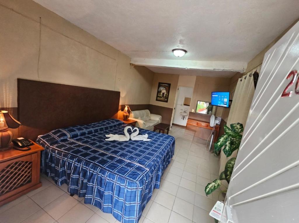 a bedroom with a bed with a blue plaid blanket at Hotel y Cabañas Manolo in El Pedregal