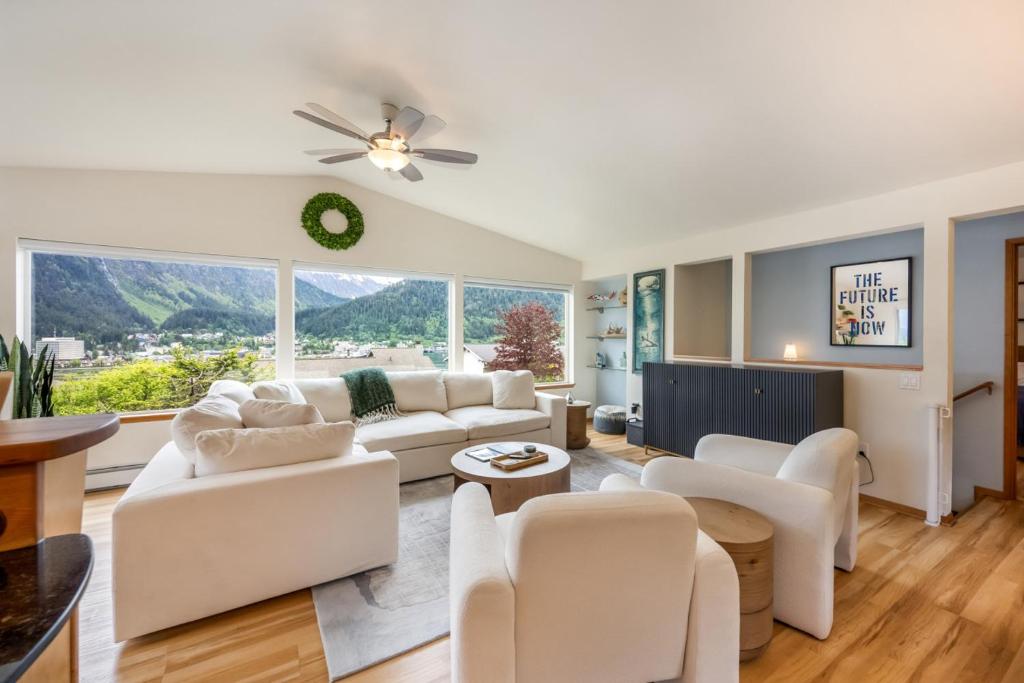 a living room with white furniture and a large window at Magical Mountain Retreat in Juneau