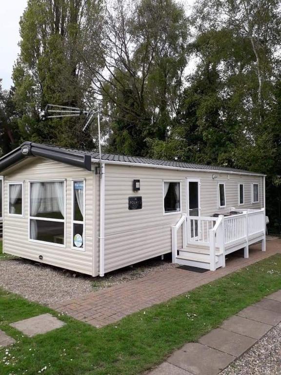 a small white house with a porch and trees at Lovely 6 berth caravan Haven wild duck hoilday park in Belton