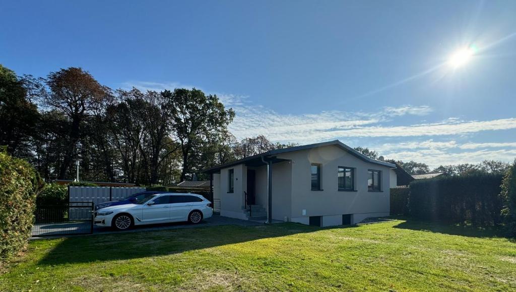 une voiture blanche garée devant une petite maison dans l'établissement Seeurlaub Haus Antonia, à Ferch