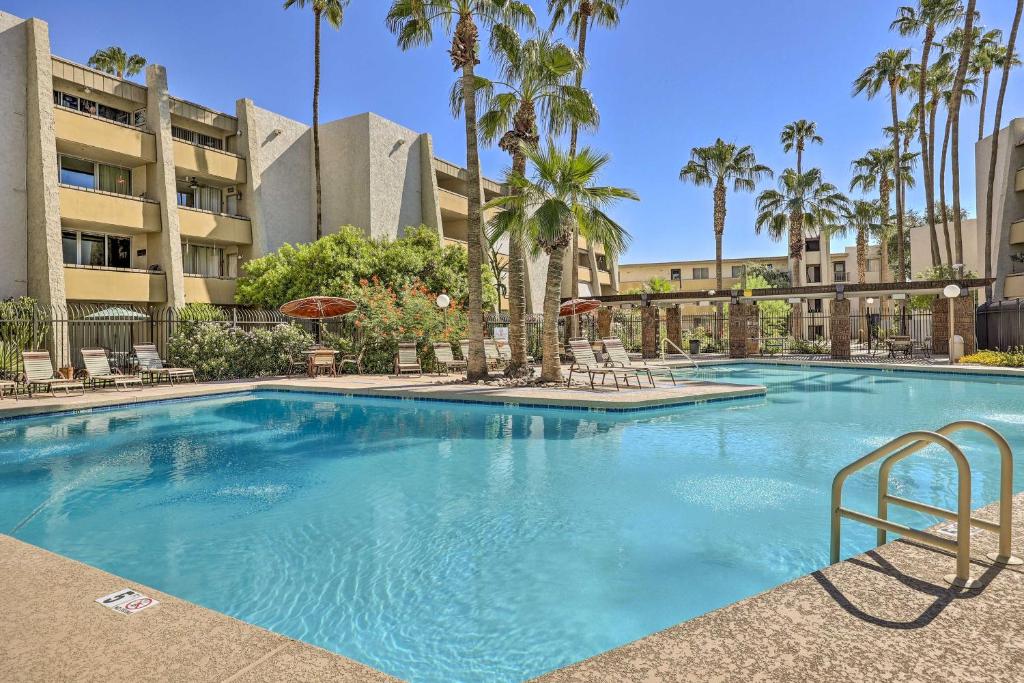 a large swimming pool with chairs and palm trees at Walkable Old Town Scottsdale Condo Pool and Hot Tub in Scottsdale