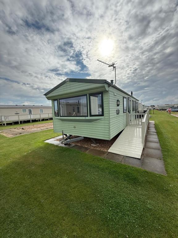 ein kleines grünes Haus auf einem Feld in der Unterkunft 8 Berth Caravan in Chapel St in Chapel Saint Leonards