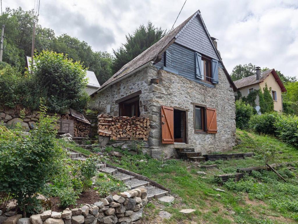 una vecchia casa in pietra con un mucchio di tronchi di Charmante grange rénovée pour 8 pers. à Aneran - FR-1-695-80 a Anéran-Camors