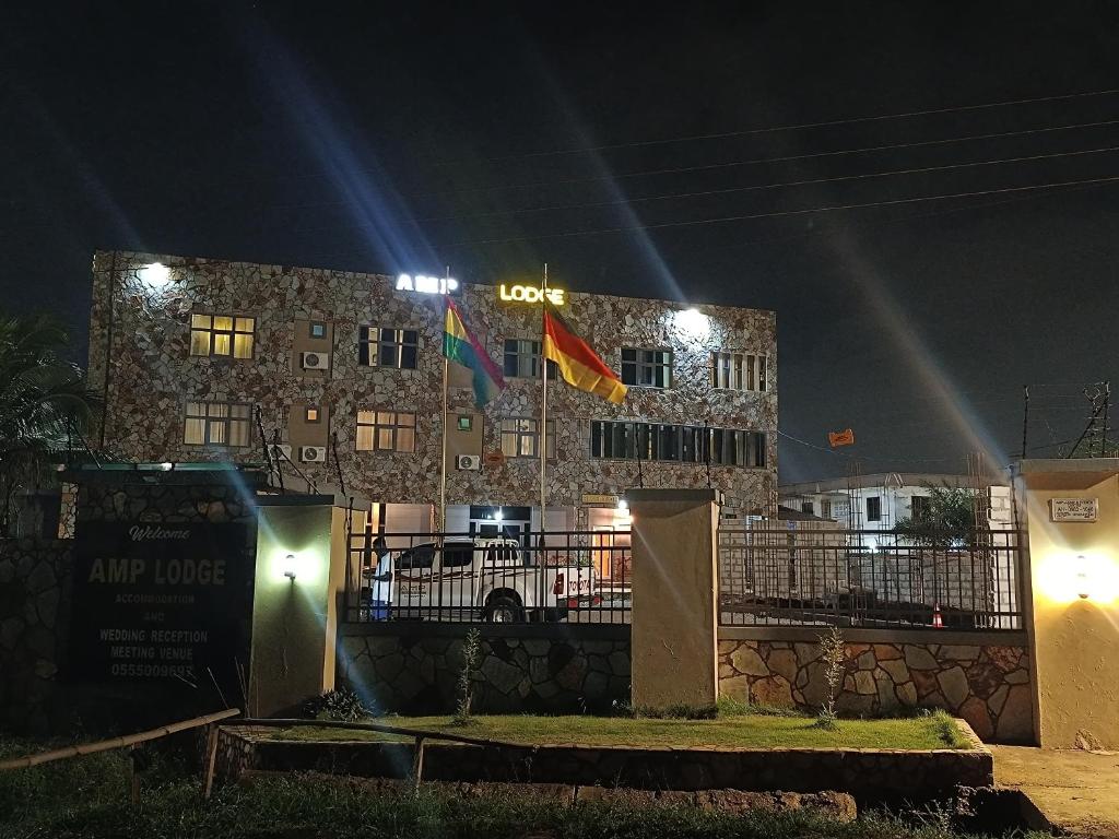 クマシにあるAMP Lodgeの夜間の看板付きの建物