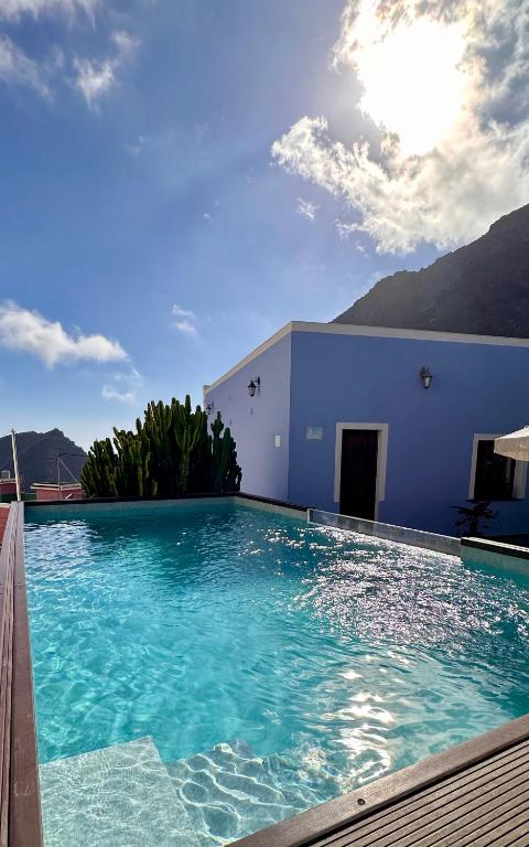 a large swimming pool with a blue building and mountains at Casa Regina Tenerife in Tamaimo