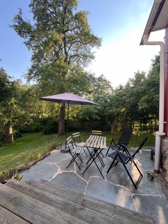 un patio avec deux chaises et un parasol dans l'établissement Charming Countryside Cottage, à Varekil
