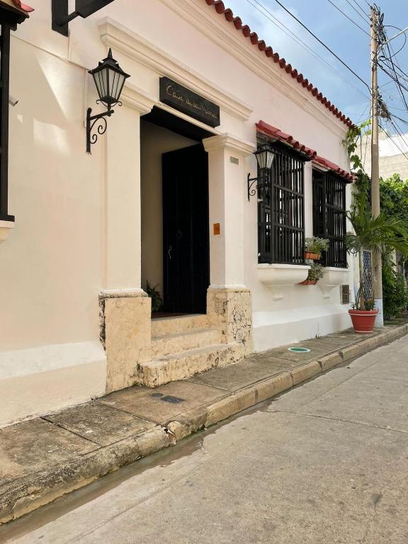 a white building with a black door on a street at Hotel Casa de Las Palmas in Cartagena de Indias